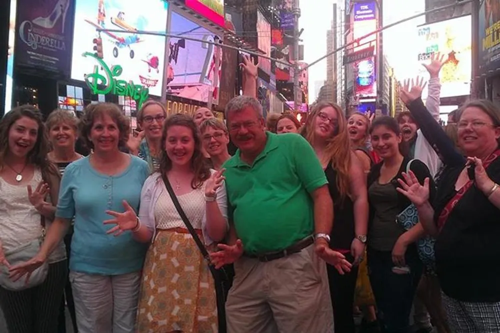 A group of cheerful people is posing for a photo in Times Square with brightly lit billboards and advertisements in the background