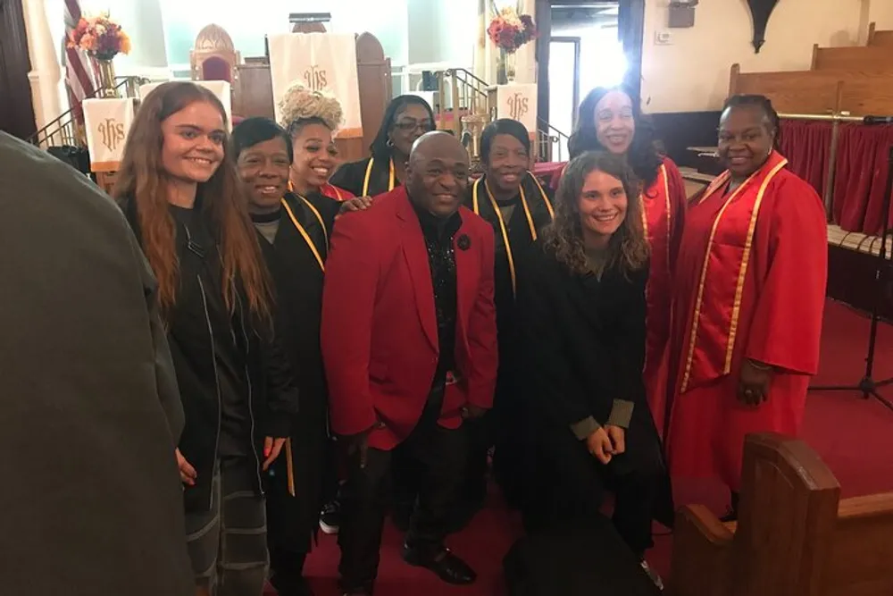 A group of smiling people some in red and gold choir robes are posing for a photo inside a church