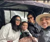 Four people are smiling for a selfie while seated in a horse-drawn carriage creating a moment of shared happiness