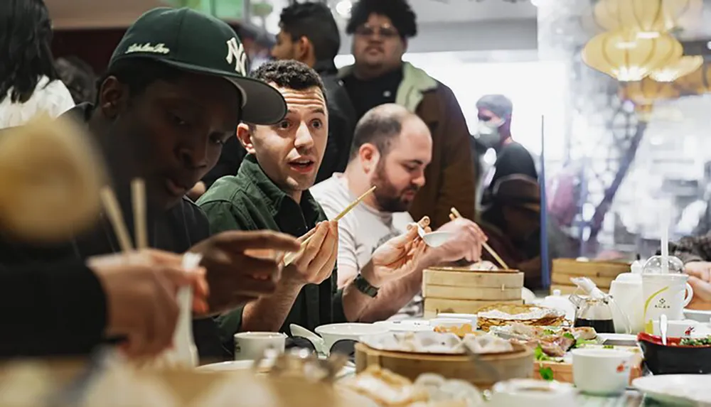 A group of people are enjoying a meal together at a dim sum restaurant with various dishes spread out on the table in front of them