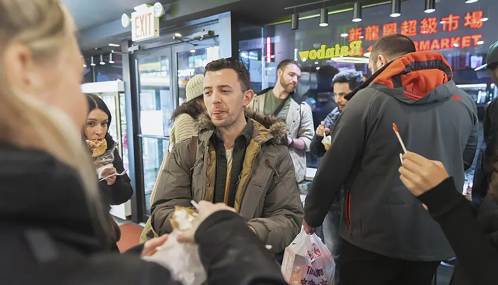 People are engaged in casual eating and conversation at an indoor location with a visible FOOD MARKET sign in the background