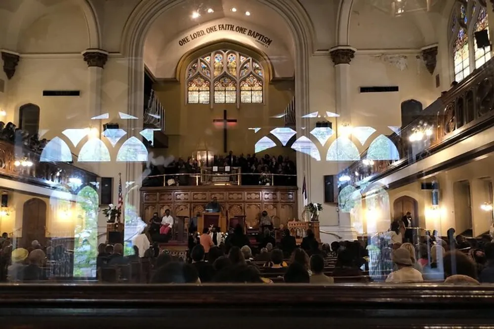 This image shows a congregation inside a church with vaulted ceilings and stained glass windows focusing on a service or a choir performance at the front