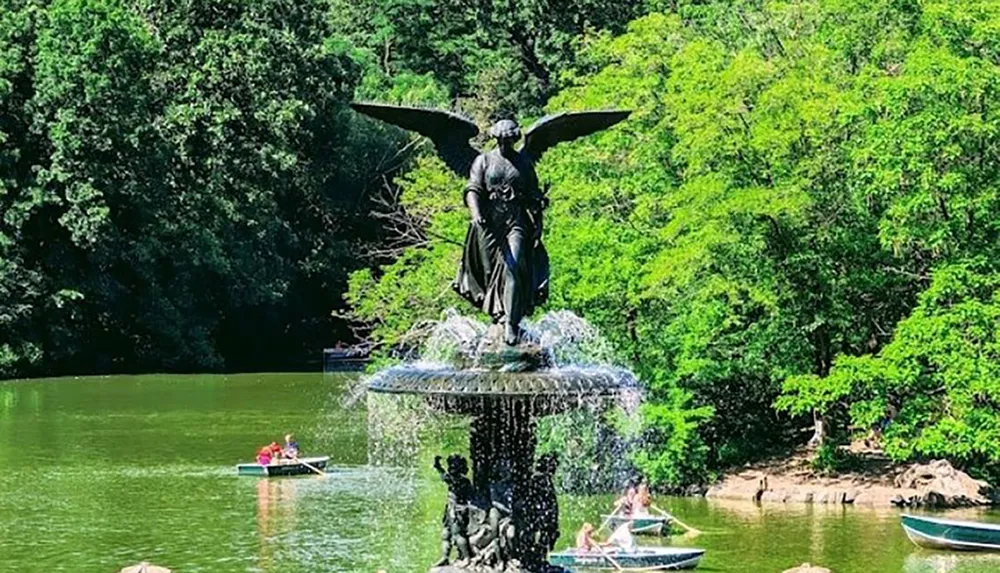 This image shows a scenic view of a fountain with an angelic statue surrounded by lush greenery with people rowing boats on the tranquil pond it overlooks