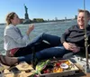 Two people are enjoying a picnic on a boat with the Statue of Liberty in the background