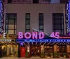 The image shows the brightly lit neon sign of Bond 45 a New York Italian kitchen and bar with the Hotel Edison sign displayed above it