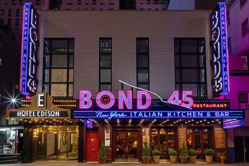 The image shows the brightly lit neon sign of Bond 45 a New York Italian kitchen and bar with the Hotel Edison sign displayed above it