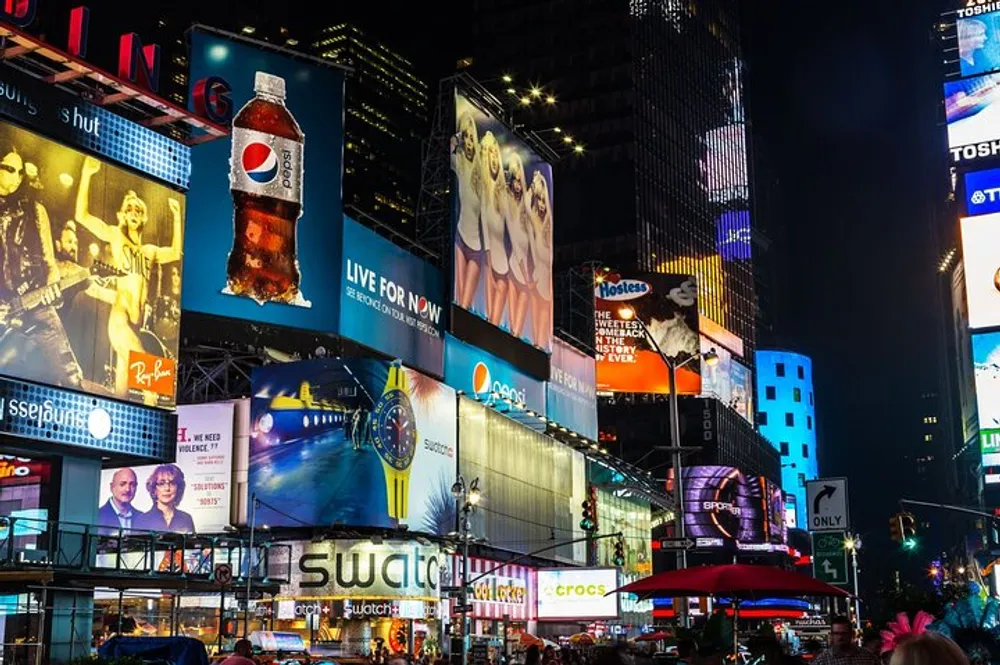 This image shows the vibrant and illuminated billboards of Times Square at night reflecting the bustling commercial and entertainment hub of New York City