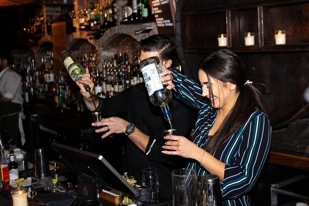 Two bartenders are pouring spirits into glasses at a busy bar