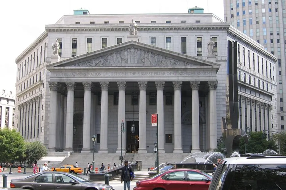 The image shows the imposing facade of a neoclassical courthouse with large columns pedestrians and vehicles in the foreground