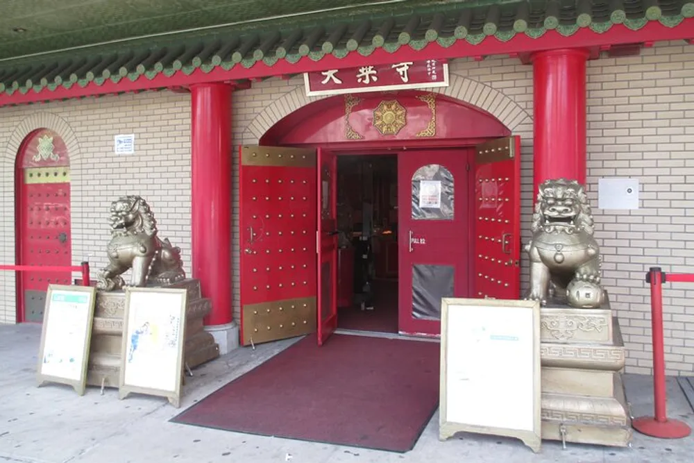 The image shows the entrance of a building adorned with traditional Chinese architectural details including a pair of lion statues guarding the red doors