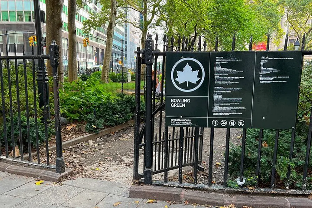 This image shows an open gate leading to Bowling Green park in an urban setting with a signpost displaying park information and regulations