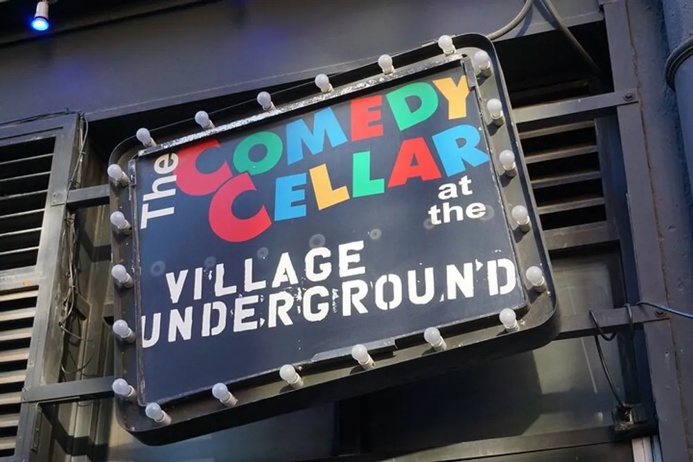 The image shows a colorful and illuminated sign for The Comedy Cellar at the Village Underground