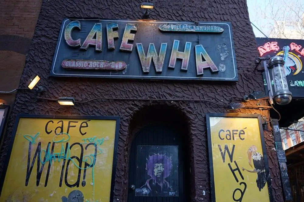 The image shows the eclectic and somewhat worn exterior of the Cafe Wha a music venue with graffiti and posters featuring a stylized depiction of a face in a window evoking a sense of urban history and culture