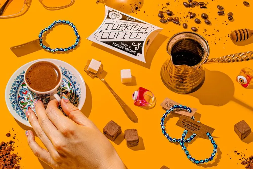 A colorful composition featuring a hand holding a cup of traditional Turkish coffee with related items such as a coffee pot sugar cubes chocolates and decorative elements arranged on a vibrant yellow background