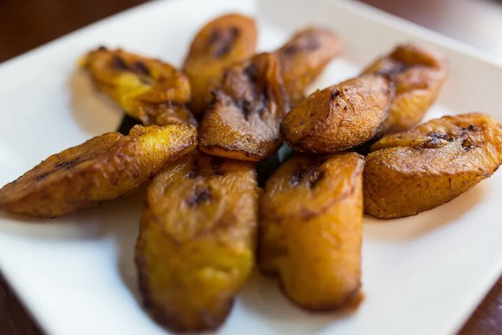 The image shows a plate of fried plantains golden brown and caramelized arranged on a white rectangular plate