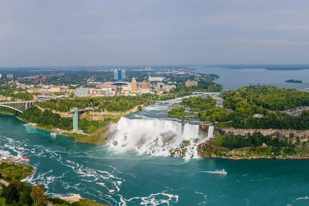 The image captures an aerial view of Niagara Falls with its cascading waters a surrounding lush landscape and nearby urban development