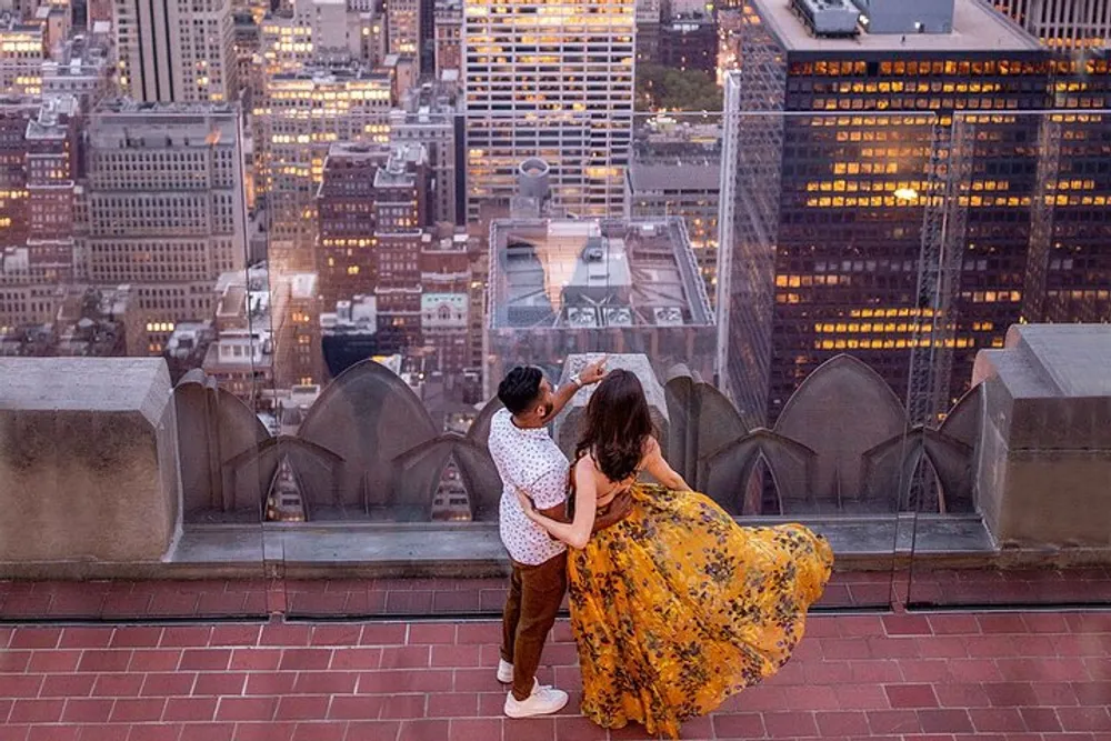 Two people are enjoying a cityscape view from a high vantage point at dusk