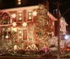 The image shows a brick house elaborately decorated with numerous Christmas lights and festive decorations including a nativity scene