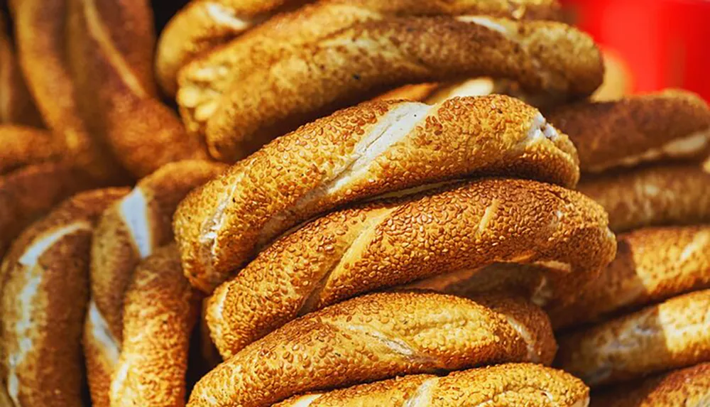 The image showcases a stack of sesame seed-covered bagels with a warm golden-brown crust