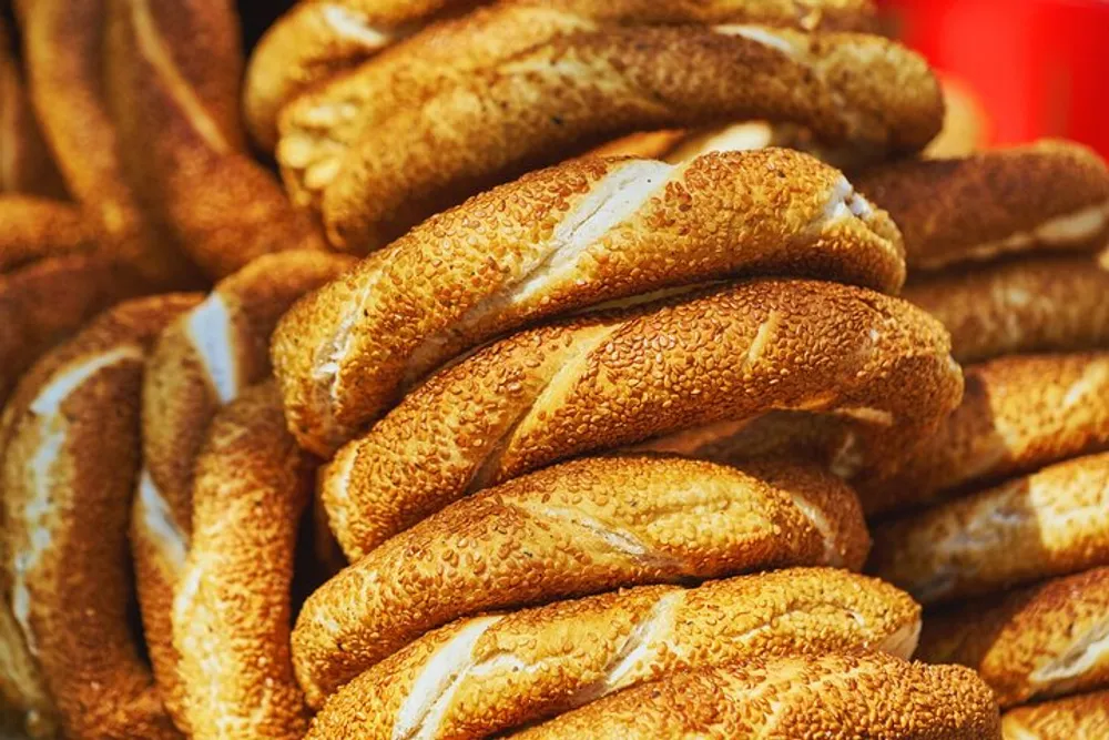 A stack of sesame-coated bagels is displayed in close-up showing their golden-brown crust and texture