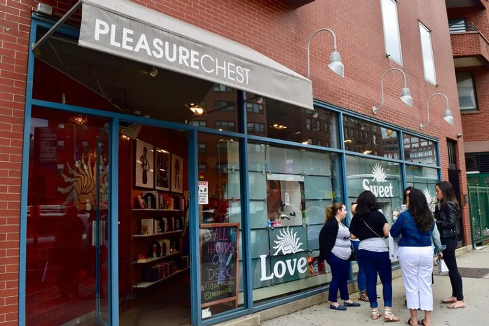 A group of people are standing outside the Pleasure Chest store which advertises love-themed products and events
