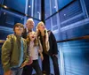 A family is looking up with expressions of awe and excitement while standing in what appears to be a glass elevator or enclosure