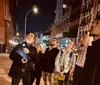 A group of people is sitting and standing on a city sidewalk at night engaging in conversation near a building labeled THE COOPER UNION