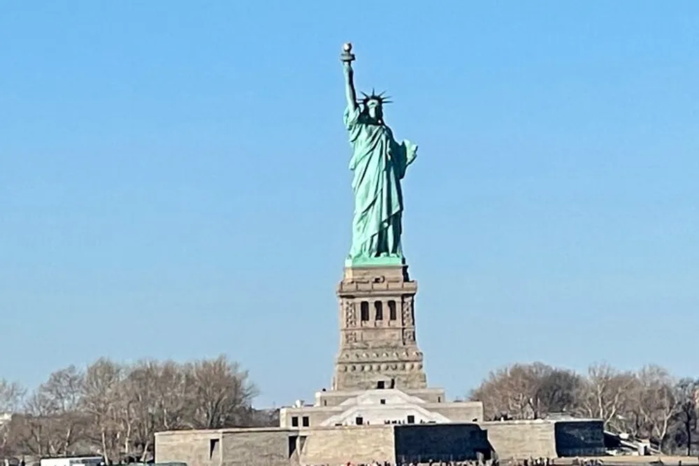 The image showcases the Statue of Liberty against a clear blue sky symbolizing freedom and democracy
