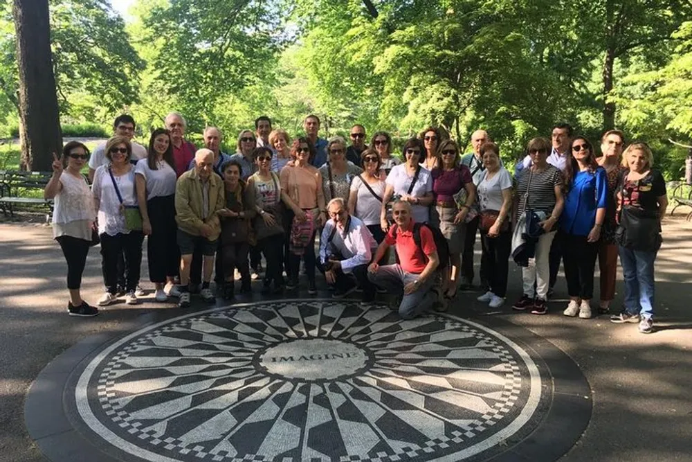 A group of people is gathered around the Imagine mosaic memorial in Central Park likely tourists or fans paying tribute