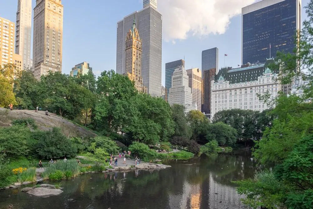 The image shows a serene pond in Central Park with people enjoying the outdoors set against the contrasting backdrop of towering New York City skyscrapers