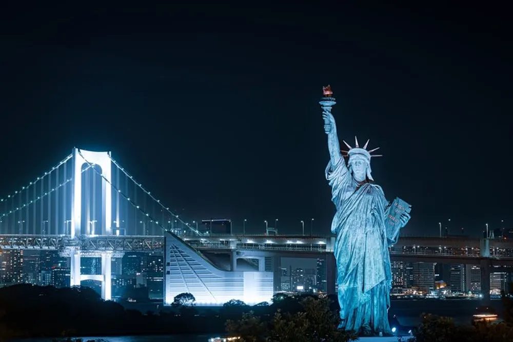 The image features a replica of the Statue of Liberty with a backdrop of a lit suspension bridge at night
