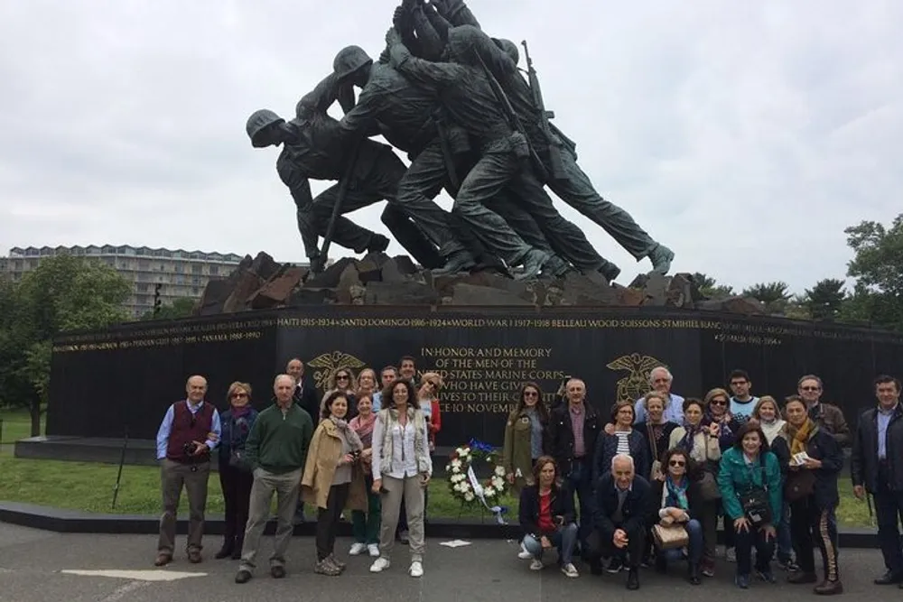 A group of visitors poses in front of a large dynamic war memorial statue commemorating military service