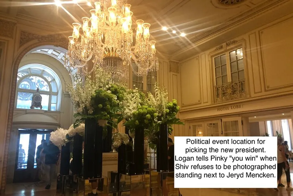 The image shows an elegant hotel lobby with chandeliers and floral decorations and there is a caption overlay describing a scene from a political event