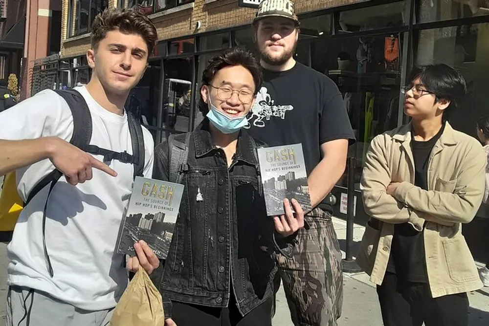 Four individuals are standing outdoors with three of them holding copies of a book titled CASH and one person pointing at a book while two of them smile at the camera and two look on