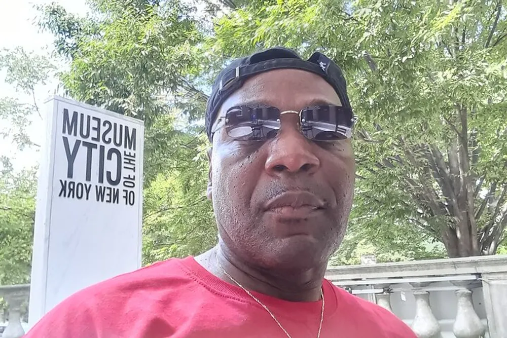 A person is taking a selfie with a sign reading MUSEUM OF THE CITY OF NEW YORK visible in the background