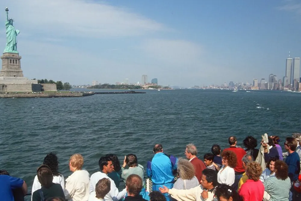 A group of people on a boat are admiring the Statue of Liberty and the New York City skyline