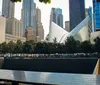 The image showcases a vibrant urban scene with the iconic One World Trade Center towering in the background adjacent to distinctive architecture and a colorful mural under a clear blue sky