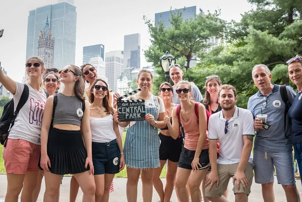 A group of tourists poses with smiles near a sign that says On Location Central Park likely during a guided tour