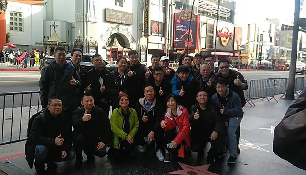 A group of people is posing with thumbs up in front of the TCL Chinese Theatre in Hollywood