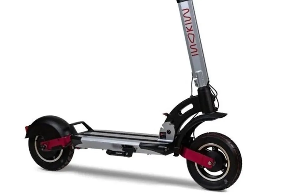 This image shows a modern electric kick scooter with a predominantly silver and black color scheme and a touch of red on the wheels standing against a white background