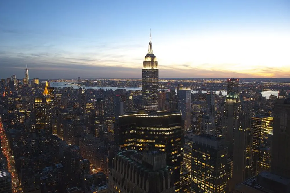 The image captures a dusk view of the New York City skyline with the Empire State Building prominently in the foreground