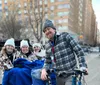 A group of smiling people are enjoying a pedicab ride on a city street during a chilly day