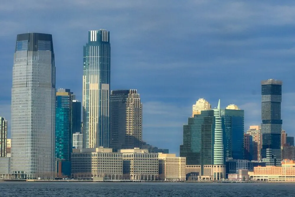 The image showcases a view of a modern city skyline with tall skyscrapers towering over the waterfront under a cloudy sky