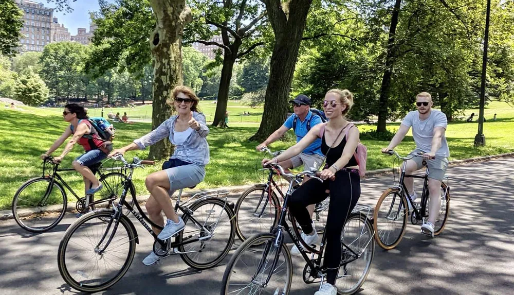 A group of people are happily riding bicycles on a sunny day in a lush green park