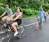 Four people are riding bicycles on a park path enjoying a sunny day outdoors