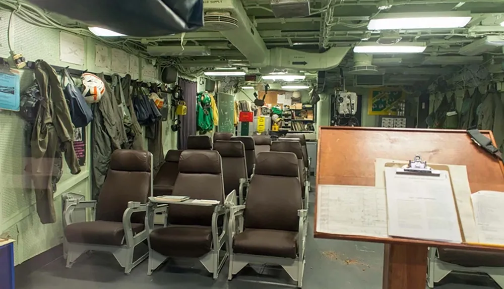 The image depicts the interior of a military aircraft with rows of seats and operational equipment evoking a utilitarian and functional atmosphere