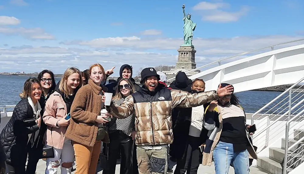 A group of cheerful people is posing for a photo in front of the Statue of Liberty