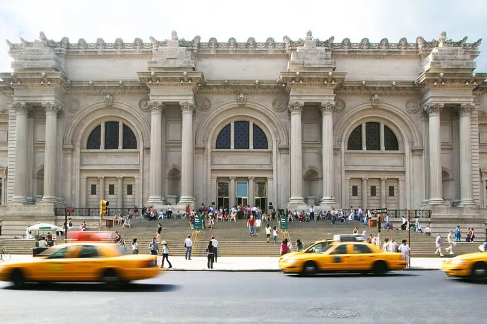 The image depicts a bustling scene outside a grand historical building with a classical facade where people are ascending the steps and taxis are driving by in the foreground