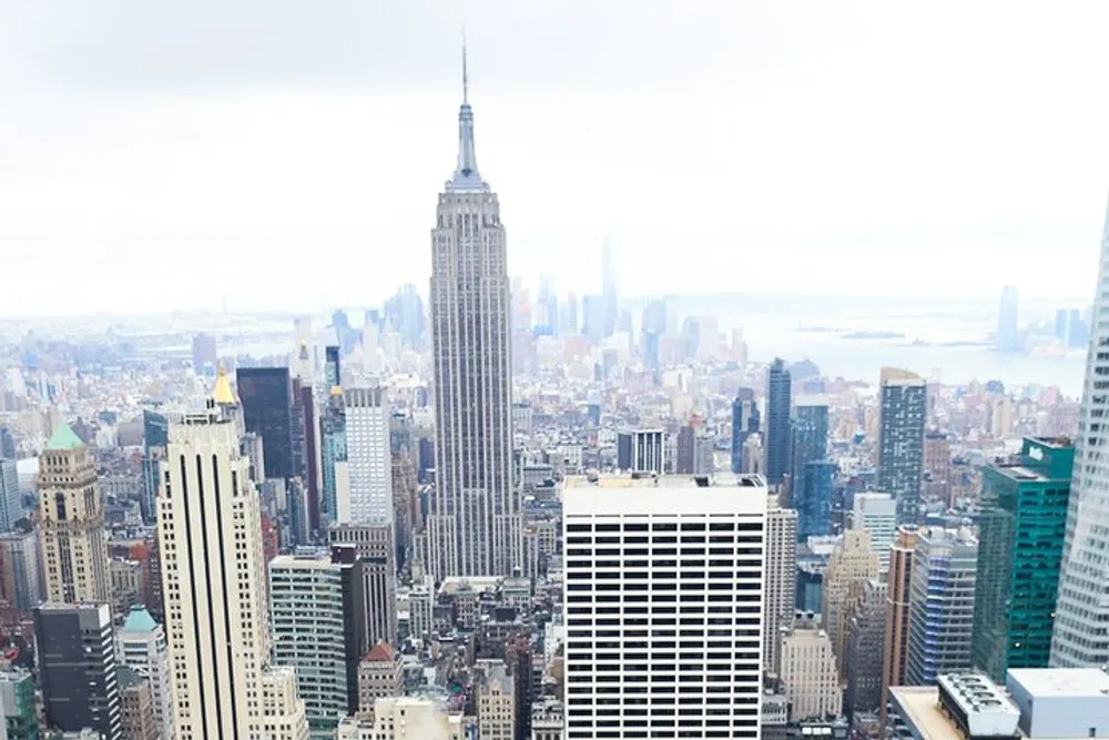 The image shows a birds-eye view of the New York City skyline with the Empire State Building prominently centered among the surrounding skyscrapers