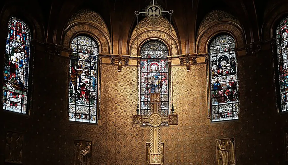 An ornately decorated church interior featuring stained glass windows and a large crucifix on a patterned gold wall